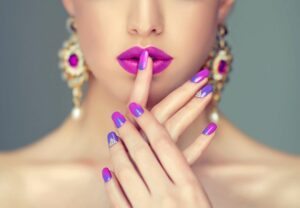 A woman with purple nails and pink lipstick.