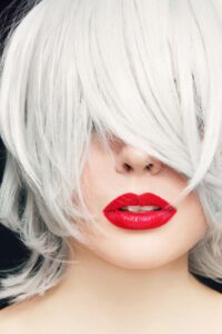 Woman with platinum blonde hair covering eyes and bold red lipstick.